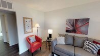 This single-story unit presents a well-organized layout designed for comfortable everyday living. The living room serves as a central gathering space, featuring durable wood-style flooring, neutral walls, and a sliding glass door that allows natural light to filter in while providing outdoor access. The open feel is complemented by a textured ceiling and ample wall space for décor.

Adjacent to the living area, the dining room offers additional natural light through a window fitted with blinds, and is equipped with a ceiling fan overhead. Wood-style flooring continues here, creating a cohesive flow between the common areas.

The galley-style kitchen is efficiently designed with warm-toned cabinetry lining both sides, dark granite-style countertops, a double stainless steel sink, and black appliances including a range, microwave, and refrigerator. Recessed lighting illuminates the workspace effectively.

The bedroom features soft carpeting, a window for natural light, and a closet, providing a calm and restful environment. The bathroom includes a full tub and shower combination with white tile surround, wood-style flooring, and a vanity with granite-style countertops, completing the unit's practical and consistent interior design.