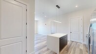 Located on the penthouse level at 196 Dayton Ave in Passaic, NJ, this thoughtfully designed 2-bedroom, 2-bathroom residence delivers a clean, modern aesthetic across a well-utilized single floor. Light-toned wood-style flooring runs throughout, creating a cohesive and airy feel in every room.

The kitchen is a standout feature, boasting bold navy cabinetry that extends floor to ceiling, a matching center island with a crisp white countertop, a dark tile backsplash, and a full suite of stainless steel appliances including a gas range, built-in microwave, and a French door refrigerator. Pendant lighting adds a refined touch above the island.

Both bedrooms are generously proportioned, featuring neutral walls, recessed lighting, and windows that invite natural light and outdoor views. The spacious primary bedroom includes a dedicated closet. Each room is equipped with a wall-mounted HVAC unit for individual climate control.

The two bathrooms are finished with contemporary style. One features a floating navy vanity with a white basin, black fixtures, and a framed mirror. The second bathroom offers a full tub-shower combination enclosed by sliding glass doors, complemented by large-format tile surround, a matching navy vanity, and black-framed mirror — both spaces conveying a polished, hotel-like quality.
