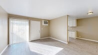 This single-story, one-bedroom, one-bathroom unit offers a practical and well-organized layout across a modest but efficiently utilized footprint. The living room serves as the central gathering space, finished with light wood-look tile flooring and neutral warm-beige walls that carry consistently throughout the unit. Vertical blinds on the windows and sliding door allow for adjustable natural light, and a wall-mounted A/C unit provides climate control. The space connects directly to the galley-style kitchen, which features white cabinetry extending to the upper walls for ample storage, granite-look countertops, a stainless steel sink, and a black gas range with an overhead exhaust hood. A window at the end of the kitchen allows additional natural light into the cooking area. The generously sized primary bedroom accommodates substantial furnishings comfortably and includes a built-in closet with a rod and shelf for organized storage. The bathroom is equipped with a full tub-shower combination surrounded by white square tile, complemented by a small operable window for ventilation. A hallway connects the rooms, contributing to the unit's straightforward and functional flow.