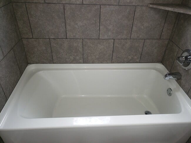 Large soaking tub surrounded in gray tile and frosted window for natural lightning - 2713 Jenkins St