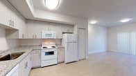 This well-designed single-floor unit offers a clean, modern aesthetic throughout, characterized by a neutral color palette, light wood-style flooring, and crisp white walls that create a bright and airy atmosphere.

The kitchen is thoughtfully laid out in an L-shaped configuration, featuring light-toned cabinetry with sleek bar-pull hardware, granite-look countertops, and a full suite of white appliances including a refrigerator, electric range, over-the-range microwave, and dishwasher. Flush-mounted ceiling lighting illuminates the space effectively, and a dedicated entry door is conveniently located just off the kitchen area.

The living and dining areas offer an open, flexible layout with generous wall space and light-colored flooring that flows seamlessly throughout. A sliding glass door fitted with vertical blinds provides access to an outdoor area and allows natural light to pour in. An electrical panel is discretely integrated into the living area wall.

The bedroom features multiple windows dressed with vertical blinds, allowing abundant natural light while maintaining privacy. A ceiling fan adds comfort to the room.

The bathroom is finished with large-format light tile flooring, a dark-toned vanity with granite countertop and integrated sink, a full soaking tub with overhead shower, and a frosted window that brings in diffused natural light. The overall ambiance of this unit is clean, contemporary, and move-in ready.