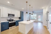 Located at 2291 Mercantile St in Castle Rock, CO, this well-appointed 1-bedroom, 1-bathroom residence offers a thoughtfully designed layout with modern finishes throughout. The open-concept kitchen and living area serves as the heart of the home, featuring striking two-tone cabinetry with crisp white upper cabinets and bold navy lower cabinets, a geometric hexagon tile backsplash, and a full suite of stainless steel appliances. A large central island with a white quartz countertop and an integrated sink is illuminated by a trio of brass pendant lights, creating both a functional workspace and a stylish focal point. Light-toned hardwood-style flooring flows seamlessly throughout, complementing the bright, neutral palette. The living area receives ample natural light through large windows and offers direct access to a private balcony with neighborhood views. The bedroom is a comfortable retreat, equipped with a ceiling fan and a generously sized window that fills the room with natural light. Two closets provide practical storage. The bathroom features a soaking tub and shower combination set within elegant large-format tile surround and accented with matte black fixtures. Additional conveniences include a dedicated laundry area and a utility room, rounding out this efficient and stylish Castle Rock residence.