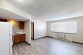 Located at 1200 Meadowview Dr in Marion, Iowa, this single-floor unit offers three bedrooms, one bathroom, a living room, and a kitchen within a compact, efficiently organized layout. Light wood-style vinyl flooring runs throughout, complemented by neutral beige walls and dark baseboards that give the space a clean, cohesive feel. Textured ceilings add a classic touch to each room.

The kitchen features warm-toned wooden cabinetry, light countertops, and white appliances including a refrigerator, electric range, and under-cabinet range hood. An adjacent sink with additional cabinetry provides functional storage and prep space.

The living area is open and straightforward, with a window fitted with horizontal blinds allowing natural light to filter in. A wall-mounted HVAC unit provides climate control.

Each bedroom is simply appointed with light flooring, neutral walls, and windows with blinds. Several bedrooms include sliding-door closets with wooden panels, offering practical storage. Baseboard heating units are present in multiple rooms.

The bathroom is equipped with a full-size soaking tub and tub-surround with built-in shelving, finished in clean white with chrome fixtures — offering a practical and tidy bathing space.