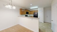 Located at 4825 Walburg Landing St in Winston Salem, NC, this single-floor residence offers a functional and well-organized layout designed for comfortable everyday living. The kitchen is a standout feature, showcasing warm wood cabinetry, granite-style countertops, and a peninsula breakfast bar that opens to the adjacent living area. Black appliances, including a refrigerator, range, and built-in microwave, are included. Tile flooring runs through the kitchen and utility areas, providing durability and easy maintenance. The living area is generously sized, featuring plush wall-to-wall carpeting and a set of French doors that open to an outdoor balcony, filling the space with natural light and providing pleasant outdoor views. The bedroom is a well-proportioned, quiet retreat finished with soft carpet and neutral walls. The bathroom features warm-toned tile flooring, wood vanity cabinetry with a granite countertop, and chrome hardware accents. A dedicated laundry room offers wire shelving, washer/dryer hookups, and tile flooring, adding practical convenience. Throughout the home, clean white walls, white panel doors, and neutral finishes create a bright, cohesive aesthetic that is move-in ready.