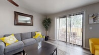 This single-floor residence in Wichita, Kansas offers a well-appointed layout with a cohesive modern design throughout. The living room features light wood-look flooring, a ceiling fan, and a large sliding glass door fitted with vertical blinds that opens to a private outdoor patio, allowing ample natural light and outdoor access. The adjacent dining area continues the wood-look flooring and is framed by a window with blinds, creating a bright and open atmosphere ideal for everyday dining. The kitchen is efficiently designed in a galley-style configuration, showcasing white cabinetry, light countertops, stainless steel appliances including a refrigerator, dishwasher, and range, and the same wood-look flooring for a seamless aesthetic. The bedrooms offer a comfortable retreat, with plush carpeting underfoot, generous natural light from windows dressed with blinds and curtains, and closet storage. The primary bedroom is a notably restful space with soft carpet, ambient lighting, and a closet. Neutral gray tones and clean finishes carry throughout the entire residence, lending a calm and contemporary feel to every room. The overall layout is practical and inviting, suited for comfortable everyday living.