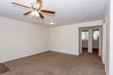 This single-story residence offers a thoughtfully arranged layout that balances open communal spaces with private quarters. The living area is generously proportioned, featuring plush wall-to-wall carpeting, neutral-toned walls, a textured ceiling, and a ceiling fan with integrated lighting. A large window fitted with horizontal blinds allows natural light to fill the space, while a nearby entry door provides direct access. The living area connects seamlessly to the kitchen, creating an open, functional flow.

The kitchen is a standout feature, showcasing dark espresso-toned cabinetry that extends to the upper and lower walls, paired with light quartz countertops and a central island that adds additional workspace and storage. Stainless steel appliances, including a dishwasher and refrigerator, complement the wood-look vinyl flooring and a window that brings in natural light.

The bedrooms continue the carpeted flooring theme, each equipped with ceiling fans, ample wall space, and windows with blinds for natural light and privacy. The bathroom is finished with dark wood cabinetry, a white countertop vanity, wood-look tile flooring, and a full tub-shower combination, maintaining a cohesive and clean aesthetic throughout the home.