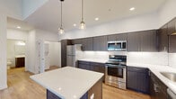 This well-designed one-bedroom, one-bathroom unit offers a thoughtfully arranged single-floor layout with modern finishes throughout. Light wood-tone flooring runs continuously across the entire unit, lending a cohesive and clean aesthetic to every room.

The open-concept kitchen and living area serves as the centerpiece of the unit. The kitchen is outfitted with dark espresso cabinetry extending floor to ceiling, a white subway tile backsplash, stainless steel appliances including a refrigerator, electric range, microwave, and dishwasher, and a center island with a crisp white quartz countertop. Pendant lighting hangs above the island, adding a contemporary touch. The living area features vaulted ceilings that amplify the sense of space, a wall-mounted mini-split system for climate control, and a sliding glass door providing natural light and outdoor access.

The bedroom is a comfortable, well-proportioned room with a window overlooking greenery, a ceiling fan, and clean white walls. The bathroom is finished with a dark wood-toned vanity, white quartz countertop, a large mirror with bar lighting, and a full bathtub with shower. A stacked in-unit washer and dryer is also conveniently included.