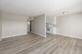 Located at 2700 Temple Crest Drive in Birmingham, Alabama, this one-bedroom, one-bathroom unit offers a well-organized layout across a single floor. The combined kitchen and living room serves as the heart of the space, featuring light wood-style flooring that runs throughout and neutral warm-toned walls that create a clean, cohesive aesthetic. The kitchen is equipped with white cabinetry, white appliances including a refrigerator and electric range, and ample counter space. The living area benefits from a large window and sliding glass doors that open onto a private balcony, where expansive views of the surrounding Birmingham treeline and skyline can be enjoyed. Natural light flows generously into the main living area. The bedroom is a comfortable, well-proportioned room with its own window, textured ceiling, and easy access to a hallway closet for added storage. The bathroom features a full tub-shower combination with white tile surround, complemented by the same light flooring found throughout the unit. A dedicated hallway connects the rooms efficiently, and the entryway provides a welcoming transition into the space. Textured ceilings are consistent throughout, adding a classic touch to the overall interior character.