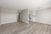 Located at 2700 Temple Crest Drive in Birmingham, Alabama, this one-bedroom, one-bathroom unit offers a well-organized layout across a single floor. The combined kitchen and living room serves as the heart of the space, featuring light wood-style flooring that runs throughout and neutral warm-toned walls that create a clean, cohesive aesthetic. The kitchen is equipped with white cabinetry, white appliances including a refrigerator and electric range, and ample counter space. The living area benefits from a large window and sliding glass doors that open onto a private balcony, where expansive views of the surrounding Birmingham treeline and skyline can be enjoyed. Natural light flows generously into the main living area. The bedroom is a comfortable, well-proportioned room with its own window, textured ceiling, and easy access to a hallway closet for added storage. The bathroom features a full tub-shower combination with white tile surround, complemented by the same light flooring found throughout the unit. A dedicated hallway connects the rooms efficiently, and the entryway provides a welcoming transition into the space. Textured ceilings are consistent throughout, adding a classic touch to the overall interior character.