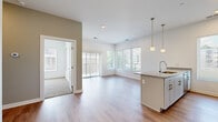 Located at 1874 E 93rd St in Cleveland, OH, this single-floor unit offers a thoughtfully designed open-concept layout finished with contemporary details throughout. The living area is bathed in natural light from large windows and a sliding glass door that leads to a private balcony, providing views of the surrounding neighborhood. Light-toned hardwood-style flooring runs through the main living spaces, contributing to a clean, modern aesthetic.

The kitchen is a functional centerpiece of the unit, featuring a granite-topped island with an undermount sink and stylish pendant lighting overhead. White cabinetry with brushed hardware lines the walls, complemented by stainless steel appliances including a range, over-the-range microwave, refrigerator, and dishwasher. Light hardwood-style flooring continues seamlessly through this space.

The bedroom offers plush carpeting, generous natural light from a large window, and convenient access to a dedicated laundry area with a stacked washer and dryer. The bathroom is finished with white tile flooring, a full tub-shower combination, and clean white cabinetry. Neutral tones and recessed lighting throughout give the unit a bright, move-in-ready feel.