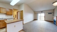 This single-floor residence offers a thoughtfully designed layout across two bedrooms and two bathrooms. The open-concept living area is defined by dramatic vaulted ceilings that rise prominently above the main living space, enhanced by a skylight in the kitchen that draws in natural light. A wood-mantled fireplace serves as a focal point in the carpeted living room, which connects directly to a private balcony through sliding glass doors, offering open outdoor views.

The kitchen is well-equipped with warm oak cabinetry, a central island featuring a granite-style countertop, tile flooring, and a full suite of appliances including a refrigerator, range, microwave, and dishwasher. The vaulted ceiling carries through into the kitchen, adding to the sense of openness.

The spacious primary bedroom offers generous proportions with plush carpeting and a large window framing open exterior views. The second bedroom is similarly carpeted and naturally lit. Both bathrooms are functional and clean, with one featuring a full tub-shower combination and oak vanity. A dedicated in-unit laundry area accommodates full-sized washer and dryer units, adding everyday convenience to this well-organized home.