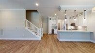 Located at 17014 Fairmount Way in Charlotte, NC, this well-appointed two-story home combines classic design with modern finishes. The main level features warm hardwood-style flooring, crown molding, and an open layout that connects the living area to the kitchen seamlessly. The kitchen is a standout, outfitted with crisp white shaker cabinetry extending to the ceiling, stainless steel appliances including a gas range, microwave, and French door refrigerator, a light quartz countertop, subway tile backsplash, pendant lighting over the island, and a dedicated built-in wine cooler with glass-front display cabinets. A charming staircase with white balusters leads to the upper level. A convenient powder room on the main floor features a pedestal sink and hardwood-style flooring. The upper level offers carpeted bedrooms, including one with vaulted ceilings and natural light from a large window. Bathrooms are finished with large-format tile, including a full bath with a tub/shower combination, and a spacious primary bath featuring a tiled soaking tub surround with a built-in shelf. Each bedroom includes a ceiling fan and ample natural light.