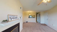The Belmont's 2-bedroom, 2-bathroom residence is a thoughtfully designed single-level home that balances comfort and functionality. The living room serves as the heart of the space, featuring a classic fireplace with a white mantel, soft carpeting, and a ceiling fan overhead. An open pass-through connects the living area to the kitchen, enhancing the sense of flow and connectivity throughout the home.

The kitchen is well-appointed with warm oak cabinetry, granite-style countertops, stainless steel appliances including a refrigerator and electric range, hardwood-style flooring, and a dedicated pantry closet offering ample storage.

Both bedrooms are generously sized with plush carpeting, ceiling fans with light fixtures, and windows that invite natural light. The primary bedroom includes a walk-in closet with built-in shelving. Each bathroom is finished with oak vanities and granite-style countertops; the primary bath features a dual-sink vanity, while the second bath includes a shower-tub combination.

Throughout the residence, warm neutral tones and consistent finishes create a cohesive, inviting ambiance. The practical layout, abundant storage, and well-maintained features make this a comfortable and move-in-ready home at The Belmont.