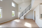 This thoughtfully designed two-story residence at 400 Riverfront Boulevard in Elmwood Park, NJ offers a modern, open layout across two well-appointed floors. The main level features a bright, open-concept living area with soaring double-height ceilings and large windows that flood the space with natural light. The contemporary kitchen is equipped with white shaker cabinetry, a light blue glass tile backsplash, white quartz countertops, stainless steel appliances including a French door refrigerator, range, microwave, and dishwasher, and a peninsula that flows seamlessly into the living area. Light hardwood flooring runs throughout the main level, complemented by a striking staircase with a sleek black metal railing. The spacious bedroom offers hardwood flooring, a generous walk-in closet with wire shelving, and a bright window with outdoor views. The full bathroom features large-format tile flooring, a white vanity, and a soaking tub with a tiled surround. Upstairs, a loft and den with plush carpeting and recessed lighting provide flexible additional living space, along with ample closet storage. A dedicated laundry area and multiple closets throughout add to the home's functional appeal.