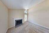 Located at 912 Peach Hill Ln in Chesterfield, MO, this two-story home offers a well-organized layout spread across two floors. The main level features a spacious living room that immediately impresses with its dramatic vaulted ceilings and a striking arched upper window that floods the space with natural light. A classic wood-burning fireplace with a tile surround and white mantel serves as the room's focal point, complemented by neutral carpet and warm beige walls. The entry area transitions seamlessly between hardwood and carpet flooring. The kitchen features white cabinetry, a peninsula with a breakfast bar, laminate countertops, and black appliances including a refrigerator, range, and microwave. Upstairs, the primary bedroom is a comfortable retreat with a ceiling fan and direct access to a closet and bathroom. The walk-in closet includes built-in wire shelving and hanging rods for organized storage. Three bathrooms serve the home, including one with a full tub-shower combination. Two dedicated closets provide ample storage throughout. The home's neutral palette, open staircase connecting both levels, and abundant windows create a bright, airy ambiance throughout this Chesterfield residence.