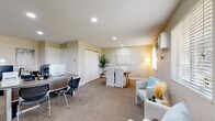 This well-appointed single-floor office space is thoughtfully designed to support a range of professional functions within an open, cohesive layout. Upon entry, a bright reception area greets visitors with large windows fitted with blinds that allow ample natural light to filter in, creating a warm and welcoming first impression. Comfortable seating with light-toned upholstered chairs and a small accent table provide a relaxed waiting environment.

The main workspace features multiple workstations equipped with desktop computers and ergonomic seating, offering ample room for staff to collaborate or work independently. A centrally located conference area with a wooden table and slipcovered chairs serves as a functional meeting zone, accented by a tall potted plant and a floor lamp that adds a touch of warmth.

A dedicated coffee and refreshment station adds a practical and inviting touch, complete with glass-front cabinetry, a single-serve coffee maker, and playful wall décor. Private offices branch off from the main area, providing quieter spaces for focused work or client meetings.

Throughout, neutral warm-toned walls, recessed lighting, and carpet flooring contribute to a calm and professional ambiance. A wall-mounted HVAC unit and baseboard heating ensure year-round comfort, making this a fully functional and thoughtfully designed professional workspace.