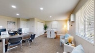 This well-appointed single-floor office space is thoughtfully designed to support a range of professional functions within an open, cohesive layout. Upon entry, a bright reception area greets visitors with large windows fitted with blinds that allow ample natural light to filter in, creating a warm and welcoming first impression. Comfortable seating with light-toned upholstered chairs and a small accent table provide a relaxed waiting environment.

The main workspace features multiple workstations equipped with desktop computers and ergonomic seating, offering ample room for staff to collaborate or work independently. A centrally located conference area with a wooden table and slipcovered chairs serves as a functional meeting zone, accented by a tall potted plant and a floor lamp that adds a touch of warmth.

A dedicated coffee and refreshment station adds a practical and inviting touch, complete with glass-front cabinetry, a single-serve coffee maker, and playful wall décor. Private offices branch off from the main area, providing quieter spaces for focused work or client meetings.

Throughout, neutral warm-toned walls, recessed lighting, and carpet flooring contribute to a calm and professional ambiance. A wall-mounted HVAC unit and baseboard heating ensure year-round comfort, making this a fully functional and thoughtfully designed professional workspace.