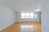 Located at 260 Wellesley St E in Toronto's vibrant Cabbagetown neighbourhood, this one-bedroom, one-bathroom unit offers a well-organized layout across a single floor. Classic parquet wood flooring runs throughout the living areas and bedroom, adding warmth and character to the space.

The living room is generously proportioned, featuring large floor-to-ceiling windows that frame views of the surrounding Toronto skyline and fill the room with abundant natural light. A baseboard heating system runs along the exterior wall beneath the windows. The textured ceiling adds a traditional residential touch throughout the main areas.

The bedroom is a comfortable, well-sized retreat with its own window offering city views, neutral grey accent walls, and the same warm parquet flooring. It provides ample space for furnishings.

The kitchen is bright and functional, fitted with white cabinetry, brushed nickel hardware, light stone-patterned countertops, and white tile flooring. It opens directly toward the living area, creating a connected feel.

The bathroom is finished with clean white subway tile surrounding a full soaking tub and shower combination, complemented by chrome fixtures for a timeless look.

This unit offers a practical and comfortable urban living space in one of Toronto's most walkable and well-connected neighbourhoods.