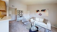This single-floor residence at 9300 SW 137 Ave offers a thoughtfully designed layout that balances comfort and functionality. The open-concept living and dining area is generously proportioned, featuring vaulted ceilings, plush carpeting, and an abundance of natural light streaming through large windows fitted with vertical blinds. The living room provides ample space for seating and relaxation, with direct sightlines into the adjoining dining area, which is anchored by an elegant chandelier and a glass-top dining table.

The kitchen features white cabinetry with warm wood-toned trim, light countertops, and a pass-through opening that connects to the dining space, enhancing the open feel of the shared living areas. Tile flooring runs through the kitchen, providing a practical and clean finish.

The primary bedroom is a comfortable retreat with carpeted floors, a ceiling fan, and sliding glass doors that open to an outdoor patio area. It is complemented by an en-suite bathroom featuring dual vanities with generous counter space, ample cabinet storage, wood-accented cabinetry, a well-lit mirror, and a separate tub and shower area.

A second bedroom also offers carpeted flooring, textured ceilings, and convenient access to an additional bathroom. Throughout the residence, a neutral color palette and consistent finishes create a cohesive and welcoming atmosphere.