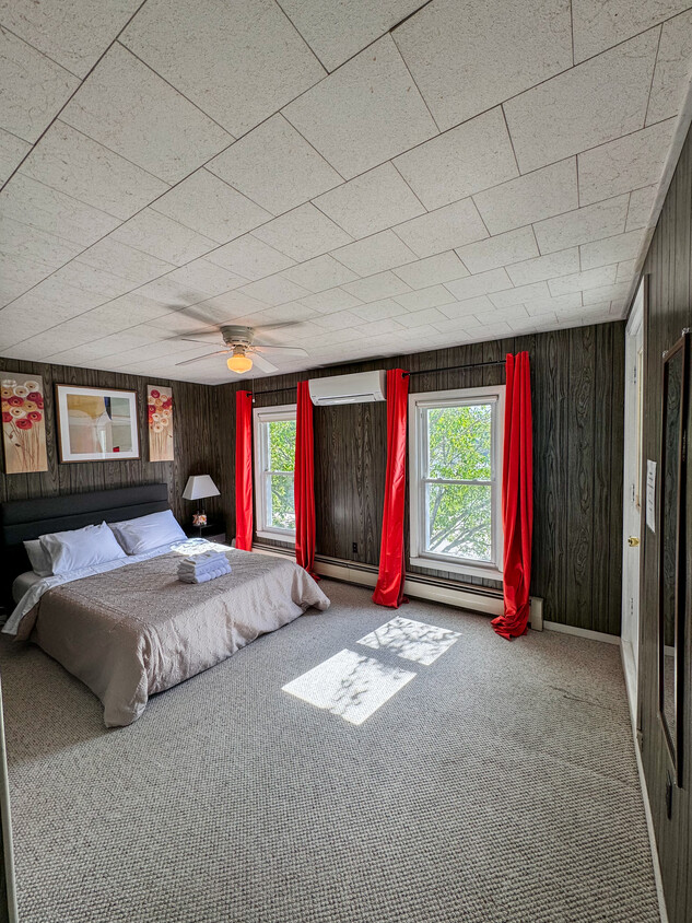 Cozy bedroom with a comfy bed, large windows for natural light, air conditioning, and a ceiling fan - 815 Mount Vernon St