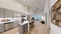 Located at 2219 E 11th St in Tulsa, OK, this single-floor, 3-bedroom, 2-bathroom residence showcases a contemporary design highlighted by dramatic, soaring ceilings that amplify the sense of space throughout. The open-concept kitchen and living area form the heart of the home, where light wood-look flooring flows seamlessly underfoot. The kitchen is well-appointed with grey shaker-style cabinetry extending to ceiling height, a classic white penny-tile backsplash, quartz countertops, stainless steel appliances, and a center island with built-in shelving — ideal for casual dining or entertaining. The living room benefits from a wall of oversized windows that flood the space with natural light and offer outdoor views, creating an airy, welcoming atmosphere. The spacious primary bedroom continues the theme of soaring ceilings and large windows, providing generous natural light and a calm retreat. The bathrooms are finished with grey cabinetry, quartz double-sink vanities, and modern fixtures, maintaining a consistent, refined aesthetic. With three comfortable bedrooms, the layout offers flexibility for a variety of living arrangements. The overall design balances modern finishes with functional living, creating a polished and inviting home.