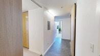 Located at 218 6th Ave in downtown Des Moines, Iowa, this 2-bedroom, 2-bathroom unit offers a well-designed, single-floor layout with a clean, modern aesthetic throughout. A welcoming entryway with light wood cabinetry and durable tile flooring leads into the main living areas.

The kitchen is fitted with warm wood cabinetry, dark countertops, stainless steel appliances, and a functional island with an integrated sink — ideal for everyday cooking and entertaining. It flows naturally into the combined living room, which features wood-look flooring, a wall-mounted television, and generous corner windows that frame expansive views of the downtown Des Moines skyline, filling the space with abundant natural light.

The primary bedroom offers a comfortable, well-proportioned space with large windows overlooking city buildings, carpeted flooring, and a calm, restful atmosphere. The second bedroom also benefits from natural light and city views. Two full bathrooms serve the unit, with one featuring a shower-tub combination with clean white finishes. A dedicated laundry room with side-by-side Bosch washer and dryer units adds everyday convenience. The hallways display light bamboo-style flooring and white walls, maintaining a bright, cohesive feel throughout the entire unit.