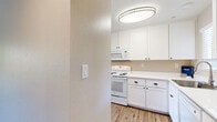 Located on High Street in Fremont, California, this 2-bedroom, 1-bathroom residence offers a well-organized single-floor layout designed for comfortable everyday living. The living room serves as the heart of the home, featuring warm hardwood-style flooring, vaulted ceilings, and a sliding glass door that opens onto a private balcony overlooking lush, mature trees. A large picture window further fills the space with natural light, creating a bright and welcoming atmosphere. An elegant chandelier adds a refined touch to the adjacent dining area.

The galley-style kitchen is efficiently designed with crisp white cabinetry, white quartz countertops, and light wood-style flooring. It comes equipped with a full suite of white appliances, including a range, over-the-range microwave, and dishwasher, along with a window above the sink that brings in additional natural light.

Both bedrooms feature plush wall-to-wall carpeting and windows that invite natural light. The primary bedroom is generously sized and includes a sliding mirrored closet, with convenient access to an in-unit washer and dryer. The full bathroom offers a clean, modern aesthetic with white cabinetry, a white countertop vanity, and wood-style flooring. A hallway connects all rooms, ensuring a functional and cohesive flow throughout the home.