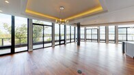 Located along West Lake Street in Minneapolis, this single-floor residence showcases a refined blend of modern design and thoughtful craftsmanship. The entry hall immediately sets an elegant tone with rich hardwood flooring, softly curved walls, and a distinctive circular tray ceiling fitted with a stylish flush-mount light fixture. The open-concept layout flows seamlessly throughout, with warm hardwood floors unifying the primary living spaces.

The chef's kitchen is a standout feature, equipped with premium stainless steel appliances including a built-in refrigerator, double wall ovens, and a professional-grade range. White shaker cabinetry with glass uppers, a marble tile backsplash, and a generous island with a gray quartz countertop and pendant lighting above complete this highly functional space.

The main living area features a tray ceiling with cove lighting and a ceiling fan, while floor-to-ceiling black-framed windows and sliding glass doors provide access to an outdoor terrace and frame lush tree canopy views. The primary bath offers a freestanding soaking tub positioned beneath expansive windows overlooking the surrounding greenery.

Additional highlights include a spacious walk-in closet with dark wood built-in shelving and a central island, a secondary walk-in closet with chrome shelving, and a powder room with a vessel sink and modern sconce lighting.