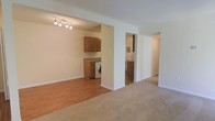 Located at 541b Tranquil Court, this single-floor residence offers a thoughtfully arranged open-concept layout that maximizes functionality and flow. The living area is finished with plush wall-to-wall carpeting, creating a warm and comfortable atmosphere, while the adjacent utility and kitchen spaces transition to durable hardwood-style flooring for easy maintenance.

The kitchen area features warm-toned wooden cabinetry paired with countertops, providing ample storage and prep space. A dedicated laundry area is conveniently integrated into the layout, housing an in-unit washer — a practical amenity that adds everyday convenience. A glimpse into the adjoining kitchen reveals additional cabinetry and a full-size range, completing a fully equipped cooking space.

The open passage design connects the living spaces naturally, with clean white walls and neutral tones throughout that lend the interior a bright, airy feel. Track lighting in the main living area provides focused illumination and a modern touch. A hallway leads further into the unit, suggesting additional private living spaces beyond. The overall design is clean, practical, and move-in ready, making this a well-rounded single-level home.
