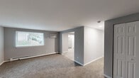 This well-organized single-floor residence in Chester, PA offers a practical and comfortable layout across two bedrooms and two bathrooms. The interior is finished with neutral gray walls and clean white trim throughout, creating a cohesive and move-in-ready aesthetic.

The living room is a generous, open space featuring plush carpeting, a wall-mounted unit, and a window that allows natural light to fill the room. It connects seamlessly to the dining area, enhancing the sense of flow throughout the common spaces. The kitchen stands out with bright white shaker-style cabinetry, granite-toned countertops, stainless steel appliances including a refrigerator and range, a single-basin sink, and light tile flooring — all illuminated by a window overlooking the outdoors.

The spacious primary bedroom offers ample room, carpeted floors, baseboard heating, a wall-mounted unit, and two windows that bring in natural light and outdoor views. The second bedroom is comparably comfortable, also carpeted and naturally lit, with its own closet featuring built-in shelving. Both bathrooms are clean and functional, with one featuring a full tub and shower surround.

A hallway connects the bedrooms and bathrooms, and additional closet storage adds practicality to this efficiently designed home.