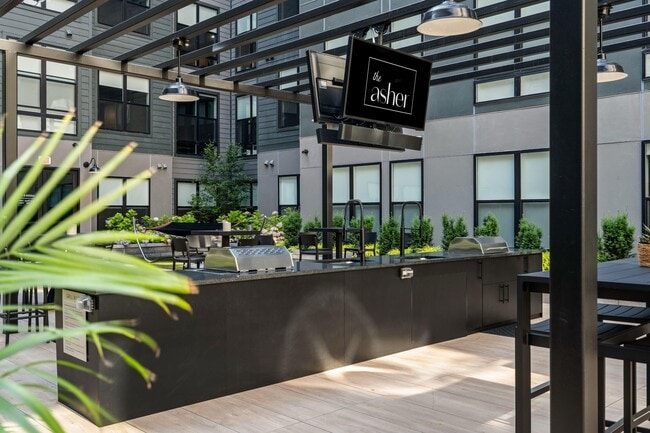 Central courtyard featuring lounge seating, bar area, outdoor tv's, and grills - The Asher