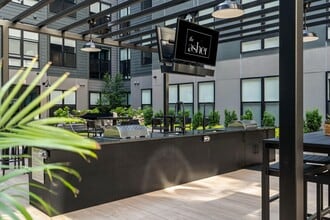 Central courtyard featuring lounge seating, bar area, outdoor tv's, and grills - The Asher