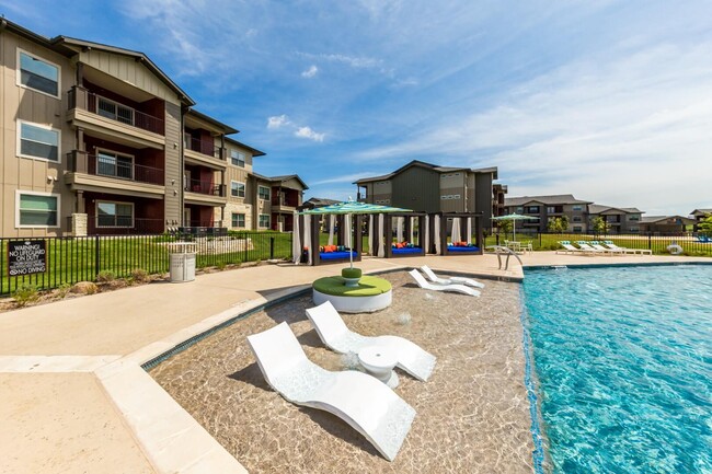 Piscina estilo centro turístico con cabañas y tumbonas - Legacy Creekside Apartments