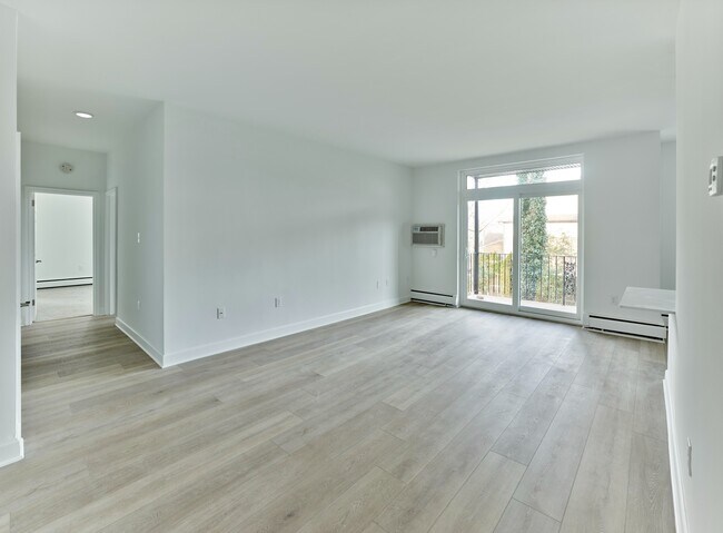 Espacio de estar abierto y ventilado con grandes ventanales y acceso al balcón en Crestwood Apartments en Wayne, PA - Crestwood