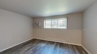 Located at 2345 Harrison Ave in East Lansing, Michigan, this one-bedroom unit offers a efficiently designed single-floor layout. The interior is finished with light wood-style luxury vinyl flooring throughout, neutral gray walls, and clean white trim, creating a bright and cohesive aesthetic.

The kitchen is a standout feature, outfitted with dark wood-grain cabinetry spanning both upper and lower sections, a sleek white countertop, and a stainless steel sink. Stainless steel appliances, including a refrigerator, microwave, and electric range, complete the space. Recessed lighting adds a modern touch and ensures the area is well-lit.

The living area is open and clean, with smooth walls and consistent flooring that carries throughout the unit. A doorway connects the main living space to the bedroom wing, which also includes built-in shelving visible through the hallway.

The bedroom is a comfortable size, featuring a window with vertical blinds that allows natural light to filter in. A set of louvered bi-fold closet doors provides ample storage. A baseboard heating unit runs along the lower wall, ensuring year-round comfort.

The unit's straightforward, modern design and functional layout make it a practical and attractive living space in the East Lansing area.
