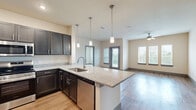 Located at 5425 E Orem Dr in Houston, TX, this single-story home offers four bedrooms, two bathrooms, and a well-designed layout that balances comfort and functionality. The open-concept kitchen is a standout feature, equipped with dark espresso cabinetry, granite countertops, a large center island with pendant lighting, a stainless steel sink, dishwasher, range, microwave, and refrigerator. The kitchen flows seamlessly into a bright living room adorned with wood-style flooring, a ceiling fan, and multiple windows that invite natural light and outdoor views. The primary bedroom is a generously sized retreat with plush carpeting and ample closet space. Additional bedrooms also feature carpet flooring and double-door closets, providing practical storage throughout. The bathrooms are elegantly finished — one includes a dual-sink vanity with granite countertops, wood-look flooring, and a walk-in shower, while the second features a full soaking tub framed by large marble-style subway tiles. The home also includes a dedicated laundry area, a patio, and a hallway connecting the well-organized floor plan. Neutral warm tones and modern finishes give the entire space a clean, contemporary feel.