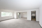 This single-floor residence offers a blend of comfort and functionality. The living areas are characterized by their spaciousness, with wall-to-wall carpeting in a neutral tone that complements the white walls. Large windows in several rooms allow for ample natural light, creating a bright and airy atmosphere.

The kitchen is a standout feature, boasting a practical L-shaped layout with ample counter space. It's equipped with modern appliances, including a built-in microwave, dishwasher, and a sleek stove. The wooden cabinetry adds a warm, traditional touch to the space, while the light-colored tile flooring ensures easy maintenance.

The residence includes multiple bathrooms, each designed for efficiency and comfort. One bathroom features a combination tub-shower, while another offers a more compact layout with just a toilet and sink. Both bathrooms have single vanities with storage space underneath.

The bedrooms are generously sized, with large windows that provide views of the surrounding area. Built-in closets offer convenient storage solutions. Throughout the home, recessed lighting and ceiling fixtures provide adjustable illumination options.

Overall, this residence presents a clean, well-maintained living space with a neutral color palette, allowing for easy personalization by its occupants.