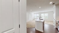 This contemporary apartment, located at Sullivan Place Two Bedroom B2A 14-5305, offers 910 square feet of thoughtfully designed living space. The layout comprises two bedrooms, including a primary bedroom of 160 square feet, and three bathrooms, providing ample privacy and convenience for residents and guests alike.

The kitchen is a standout feature, boasting warm wood-toned cabinetry, stainless steel appliances, and a sleek white countertop. The space is both functional and aesthetically pleasing, with a subway tile backsplash adding a touch of modern elegance. Adjacent to the kitchen, wood-look flooring extends into the living areas, creating a seamless flow throughout the space.

Large windows in the bedrooms and living areas flood the apartment with natural light, while offering views of the surrounding neighborhood. Plush carpeting in the bedrooms adds comfort underfoot. The bathrooms are tastefully appointed with modern fixtures, including a vanity with wooden cabinetry and a well-lit mirror.

Storage is abundant, with two dedicated closet spaces and additional built-in storage solutions throughout the apartment. The overall design aesthetic is clean and minimalist, with a predominantly white color palette that creates a sense of spaciousness and allows for personalization.

This single-floor apartment combines functionality with style, making it an ideal home for those seeking a contemporary urban living experience.
