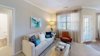 This thoughtfully designed 2-bedroom, 2-bathroom residence offers a single-floor open-concept layout that seamlessly connects the living, dining, and kitchen areas. The living room features crown molding, plush carpeting, and large windows dressed with sheer drapes and horizontal blinds that invite an abundance of natural light. A glass-top coffee table, neutral-toned sofa, and a leather accent chair complement the relaxed yet refined atmosphere.

The kitchen is outfitted with white shaker cabinetry, granite countertops, a classic white subway tile backsplash, stainless steel appliances, and a peninsula that opens to the living area. Adjacent to the kitchen, the dining area benefits from multiple windows and a pendant light fixture, creating a bright and inviting space for meals.

Both bedrooms are carpeted and well-lit, each featuring windows with sheer patterned curtains that provide privacy while allowing natural light. The two bathrooms mirror each other in style, each showcasing granite-topped vanities, wood-look flooring, and tub-shower combinations with tile surrounds. Throughout the residence, a cohesive neutral color palette, wood-look flooring in wet areas, and consistent finishes create a clean, modern, and comfortable living environment.