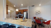 Located at 3451 Kells Way in Grove City, Ohio, this single-floor residence offers a well-designed, open-concept layout that seamlessly connects the kitchen, dining, and living areas. The kitchen is a standout feature, outfitted with rich warm-toned cabinetry, granite countertops, stainless steel appliances including a refrigerator, microwave, and range, and a peninsula with bar seating and pendant lighting. The open dining area flows naturally into a comfortable living room, which features durable hardwood-style flooring and generous natural light from multiple windows. A dedicated in-unit laundry area is conveniently accessible from the kitchen corridor. The primary bathroom is equipped with a large walk-in glass-door shower, an extended vanity with ample cabinet storage, and a well-lit mirror. A secondary bathroom features hardwood-style flooring, a vanity, and additional storage. Both bedrooms offer plush carpeting, multiple windows with blinds for privacy and natural light, and comfortable proportions suitable for a variety of furniture arrangements. Neutral wall tones throughout the residence create a cohesive and inviting ambiance, while the thoughtful floor plan maximizes functionality across every room.