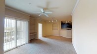 This single-story, three-bedroom, two-bathroom residence offers a thoughtfully designed layout with functional living spaces and consistent finishes throughout. The open-concept living and dining area is anchored by plush carpeting, crown molding, and a ceiling fan overhead. Track lighting illuminates the space, while built-in shelving with an arched niche provides a decorative focal point. A built-in desk nook adds a practical workspace, and vertical blinds open to natural light from the patio-facing side.

The kitchen is positioned adjacent to the living area and features dark cabinetry with brushed hardware, light countertops, tile flooring, and a full suite of black appliances including a refrigerator, range, microwave, and ample upper and lower cabinet storage.

The bedrooms are carpeted and well-proportioned. The primary bedroom benefits from a bay window configuration that invites generous natural light and outdoor views, while the secondary bedrooms each feature their own windows. Both bathrooms include tile flooring, dark vanity cabinetry with light countertops, and a tub-shower combination with tile surrounds. A dedicated in-unit laundry space accommodates a full-size washer and dryer.