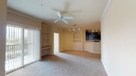 This single-story, three-bedroom, two-bathroom residence offers a thoughtfully designed layout with functional living spaces and consistent finishes throughout. The open-concept living and dining area is anchored by plush carpeting, crown molding, and a ceiling fan overhead. Track lighting illuminates the space, while built-in shelving with an arched niche provides a decorative focal point. A built-in desk nook adds a practical workspace, and vertical blinds open to natural light from the patio-facing side.

The kitchen is positioned adjacent to the living area and features dark cabinetry with brushed hardware, light countertops, tile flooring, and a full suite of black appliances including a refrigerator, range, microwave, and ample upper and lower cabinet storage.

The bedrooms are carpeted and well-proportioned. The primary bedroom benefits from a bay window configuration that invites generous natural light and outdoor views, while the secondary bedrooms each feature their own windows. Both bathrooms include tile flooring, dark vanity cabinetry with light countertops, and a tub-shower combination with tile surrounds. A dedicated in-unit laundry space accommodates a full-size washer and dryer.