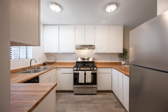 Cocina con gabinetes blancos y electrodomésticos de acero inoxidable. - Oak Park Apartments