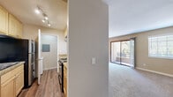 This single-story residence in San Ramon, CA offers a well-organized layout that balances comfort and functionality. The living area is generously proportioned, finished with plush neutral carpet and warmed by a ceiling fan with light fixture. Natural light fills the room through a large window fitted with horizontal blinds and a sliding glass door that opens onto a private balcony, providing pleasant outdoor views.

The galley-style kitchen is efficiently designed, featuring light wood cabinetry, granite-style countertops, and a full suite of black and stainless steel appliances including a refrigerator, gas range, and dishwasher. Wood-style plank flooring runs throughout the kitchen and hallway areas, offering durability and visual contrast to the carpeted living spaces. A pass-through counter connects the kitchen to the main living area, enhancing the open feel.

The bedrooms are spacious and carpeted, each with windows that allow natural light. Mirrored sliding closet doors add depth and storage. The bathroom corridor includes wood-style flooring and leads to a full bath with a shower/tub combination. A laundry area with in-unit washer and dryer connections is also present, adding practical convenience. Overall, the space has a clean, neutral palette throughout.