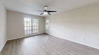 Located at 8781 White Swan Drive in Tampa, FL, this single-floor, one-bedroom, one-bathroom residence offers a thoughtfully organized layout designed for comfortable everyday living. The open living area is a highlight of the home, featuring light-toned wood-style flooring, neutral warm-gray walls, and a modern ceiling fan with integrated lighting. Large windows dressed with horizontal blinds fill the space with generous natural light and offer views of the surrounding greenery. A door from the living area provides convenient exterior access. The layout flows seamlessly from the living space into a functional kitchen area, which includes a sink and cabinetry, visible from the main living zone. The bedroom is a well-proportioned retreat, also finished with matching wood-style flooring, a ceiling fan, and a bright window that continues the home's airy, light-filled aesthetic. A closet provides dedicated storage. The bathroom is clean and practical, featuring tile flooring, a tub/shower combination with white tile surround, a toilet, and a vanity with a dark wood-tone countertop, white cabinetry, and a large mirror. Throughout the residence, consistent neutral tones and modern fixtures create a cohesive, move-in-ready environment.