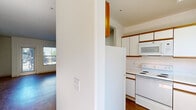 Located at 840 C St in San Rafael, California, this two-bedroom, one-bathroom residence offers a practical and well-organized single-floor layout. The living room features warm wood-style flooring and is bathed in natural light through a full-length glass door and adjacent window that open to outdoor views of surrounding greenery — creating a bright, welcoming atmosphere. A hallway connects the main living areas and leads to the private quarters of the home.

The kitchen is efficiently designed in a galley configuration, featuring white cabinetry with wood-tone accents, white appliances including a range, microwave, dishwasher, and refrigerator, complemented by wood-style flooring and a window above the sink for natural light.

Both bedrooms are carpeted for comfort. The primary bedroom includes a sliding-door closet and a glass sliding door opening to an outdoor area, while the second bedroom features a large window with outdoor views and a baseboard heater. Each bedroom benefits from a calm, neutral palette throughout.

The bathroom includes a single vanity with wood-tone cabinetry, a large mirror with overhead lighting, and clean white finishes. The hallway connecting all rooms features wood-style flooring and ceiling lighting, maintaining a cohesive and tidy flow throughout the residence.