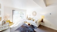 The Caspian is a thoughtfully designed two-bedroom, two-bathroom residence spanning two floors. The living room serves as the heart of the home, featuring vaulted ceilings, neutral carpet flooring, and a large sliding glass door that floods the space with natural light and opens to a private balcony with outdoor views. A decorative sunburst mirror accents the crisp white walls, complementing the warm, inviting atmosphere.

The kitchen is well-equipped with two-tone cabinetry — white uppers and gray lowers — paired with white subway tile backsplash, white countertops, and stainless steel appliances, including a range and over-the-range microwave. A window above the sink brings in additional natural light.

Both bedrooms are generously sized with plush carpet flooring and ceiling fans. The primary bedroom features a mirrored closet, while the second bedroom includes a standard closet with shelving. Each room benefits from large windows with slatted blinds that allow for adjustable natural light.

The two bathrooms are clean and modern in design. One features a glass-enclosed walk-in shower and a white dual-sink vanity with a wide mirror, while the second bathroom offers a full tub and shower combo with classic white subway tile surround. Together, these spaces offer a comfortable and functional living environment.