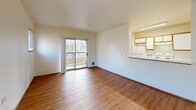 Located at 945 NW Naito Pkwy in Portland's vibrant Pearl District-adjacent waterfront corridor, this two-bedroom, one-bathroom residence offers a well-organized single-floor layout. A welcoming hallway with wood-style flooring leads into the main living spaces. The combined living and dining area is bright and open, featuring warm hardwood-style floors, large windows that invite abundant natural light and tree-lined outdoor views, and sliding glass doors that open onto a private balcony. A convenient pass-through counter connects the living area to the galley-style kitchen, which is equipped with white cabinetry featuring wood-trimmed accents, a full suite of appliances including a coil-top range, refrigerator, and dishwasher, and tile flooring for easy maintenance. Both bedrooms are carpeted and comfortably sized, each with a closet and windows providing natural light and neighborhood views. The bathroom features wood-style flooring, a single vanity with a wide mirror, and a clean, functional layout. Four closets throughout the unit provide generous storage. The overall aesthetic is clean and neutral, offering a move-in-ready canvas in a prime Portland location.