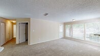 Located at 2000 Colony Park Drive in Birmingham, Alabama, this two-bedroom, one-bathroom residence offers a well-organized and comfortable single-floor layout. The living room serves as the heart of the home, featuring plush carpet flooring, a tile-surround fireplace with a classic white mantel, and a bank of large windows fitted with blinds that allow generous natural light while overlooking the tree-lined surroundings. A private balcony extends the living space outdoors, offering a peaceful view of mature trees and landscaped greenery. The kitchen is equipped with warm wood cabinetry, white countertops, black appliances including a range, dishwasher, and refrigerator, and a peninsula that connects the kitchen to the living area. Tile flooring adds practicality to this functional cooking space. Both bedrooms are carpeted and finished with neutral tones, offering a calm and restful atmosphere. The primary bedroom provides a comfortable footprint with a closet featuring bi-fold doors for convenient storage. The full bathroom includes a wood-cabinet vanity with a wide mirror, tile flooring, and a shower-tub combination. Throughout the unit, textured ceilings and consistent neutral walls create a cohesive and move-in-ready aesthetic.