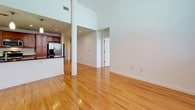 This well-appointed 2-bedroom, 2-bathroom residence offers a thoughtfully designed single-level layout that balances comfort and functionality. The open living and dining area is anchored by warm hardwood flooring and impressively tall ceilings, with structural columns adding architectural character to the space. Pendant lighting over the kitchen counter creates a natural transition between the dining and cooking areas.

The kitchen is outfitted with rich wood cabinetry, dark countertops, and a full suite of stainless steel appliances, including a side-by-side refrigerator with ice and water dispenser, an electric range, and an over-the-range microwave. Ample upper and lower cabinet storage makes this a highly functional cooking space.

Both bedrooms are carpeted and generously sized, with large windows that invite natural light. The primary bedroom includes a walk-in closet with wire shelving systems for organized storage. The two bathrooms are well-appointed — one features a clean walk-in shower with chrome fixtures and tile flooring, while the second offers a tub-shower combination with tiled surround and a vanity topped with granite countertops and warm wood cabinetry. Together, these spaces create a comfortable and practical home.